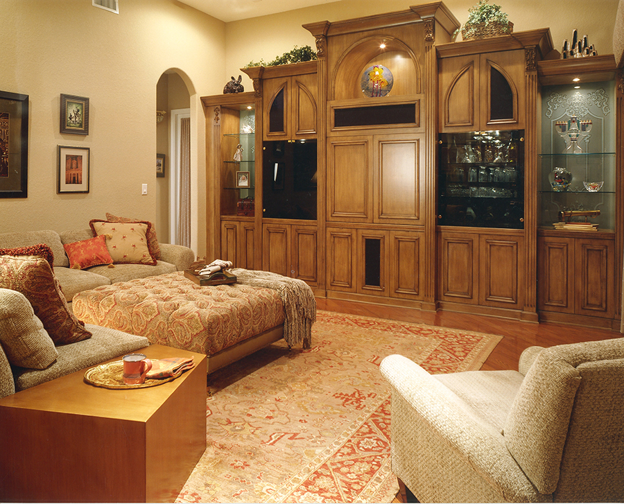 Custom wall unit in walnut and etched glass panels graces a large family room with rust and tan oriental rug